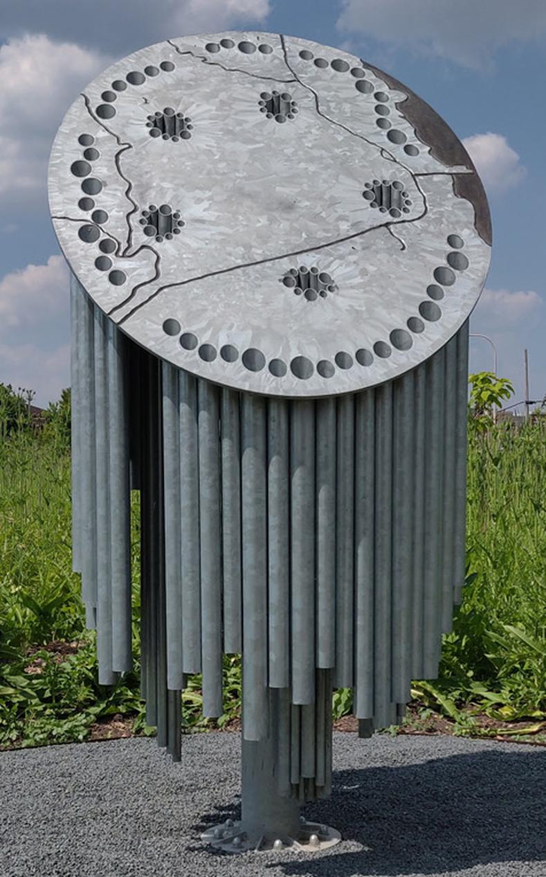 A metal sculpture with numerous holes, showcasing intricate design and craftsmanship, represents an enlarged cross-section of a willow stem